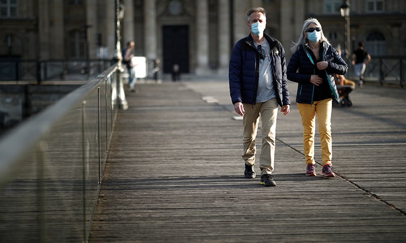 People wearing protective masks walk at the Pont des Arts bridge in Paris, France, May 2. — Reuters