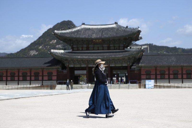 In this April 23 file photo, women wearing masks as a precaution against the new coronavirus, walk at the Gyeongbok Palace, in Seoul, South Korea. —AP