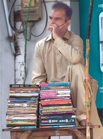 LAHORE: A vendor waits for customers as he sells second hand books during a government-imposed nationwide lockdown as a preventive measure against the coronavirus on Sunday.—AFP