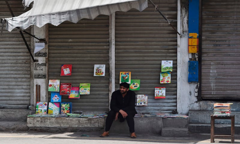 A man waits for customers as he sells books during a government-imposed nationwide lockdown as a preventive measure against the Covid-19 coronavirus, in Lahore on May 3. — AFP