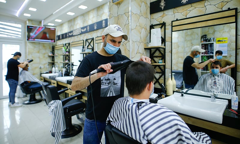 A hairdresser from the Kestir Gitsin hairdresser shop serves a customer after its reopening in Cologne, Germany, May 4. — Reuters A hairdresser from the Kestir Gitsin hairdresser shop serves a customer after its reopening in Cologne, Germany, May 4. — Reuters
