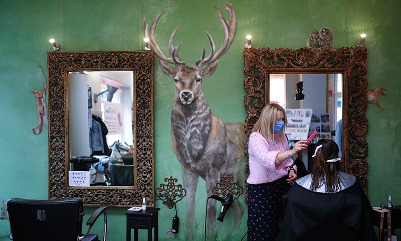 A hairdresser wears a face mask as she cuts the hair of a client at the hairdressing salon 'Haarschneider' in Dortmund, western Germany, on May 4. — AFP