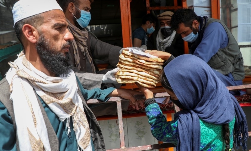 An Afghan girl receives free bread distributed by the government outside a bakery in Kabul on May 3. — Reuters