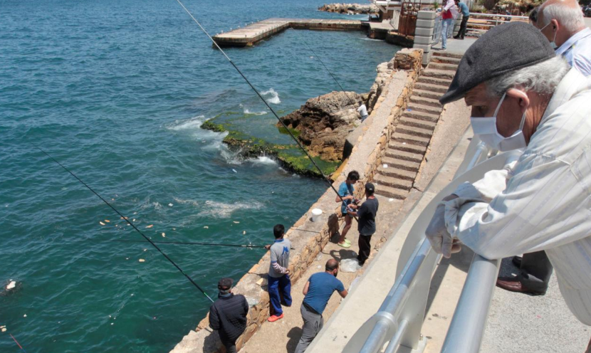 An elderly man wearing a protective face mask watches fishermen dangle their lines to catch fish as Lebanon begins to ease nationwide lockdown due to spread of Covid-19 at Beirut's seaside Corniche, Lebanon, May 4. — Reuters