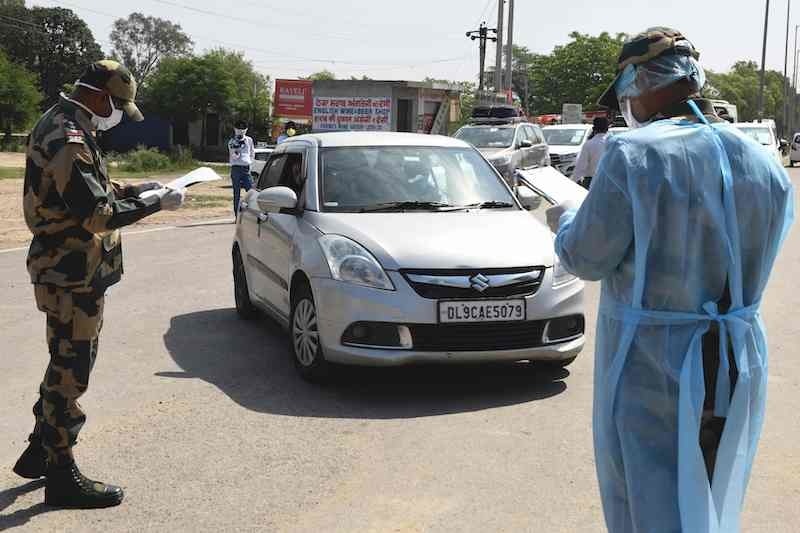 Border Security Force (BSF) personnel check the names of Pakistani nationals, who were stranded in India following the closure of borders due to the coronavirus lockdown, travelling by car before returning to their country via the India-Pakistan Wagah border post. — AFP