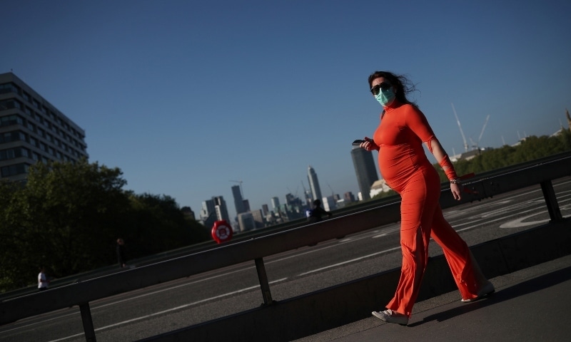 A woman wearing a protective face mask walks across Westminster Bridge in London on May 6. — Reuters