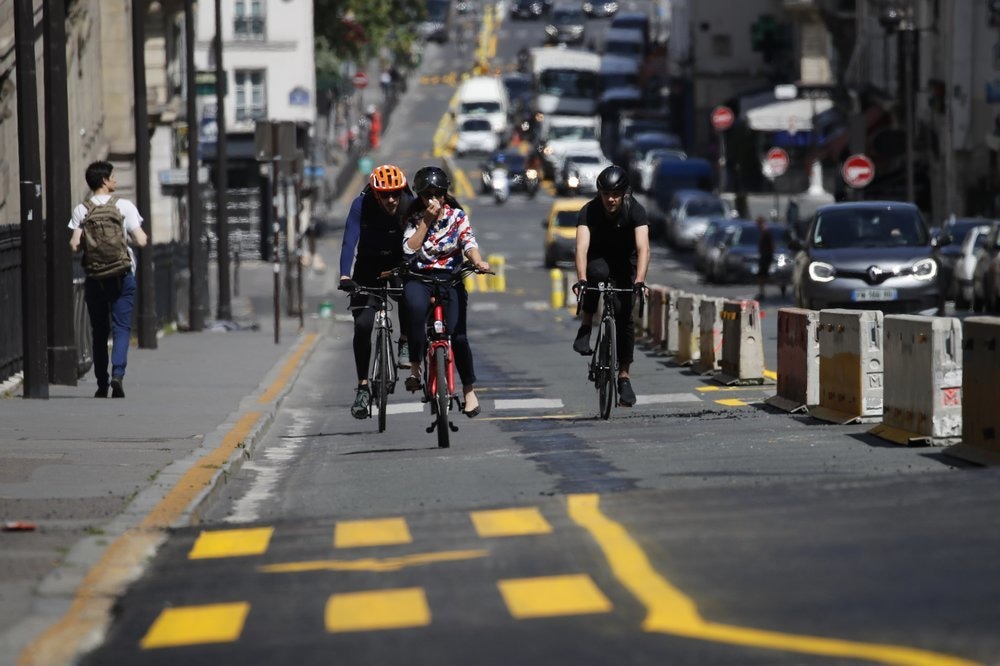 People ride on the new bike lanes on May 7 in Paris. The French capital enlarged bicycles lanes, shown with yellow painting, as it prepares the end of lockdown next Monday. — AP