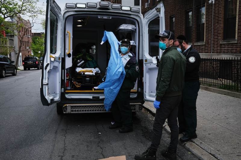 Medics suit up in personal protective equipment as they prepare to pick up a patient in severe respiratory distress from a group home next to Maimonides Medical Center on May 11, 2020 in the Borough Park neighbourhood of the Brooklyn borough of New York City. — AFP