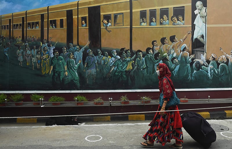 A passenger walks past a wall graffiti featuring the father of the nation Mahatma Gandhi as she enters the Howrah railway station to catch the New Delhi bound train in Kolkata on May 12. — AFP