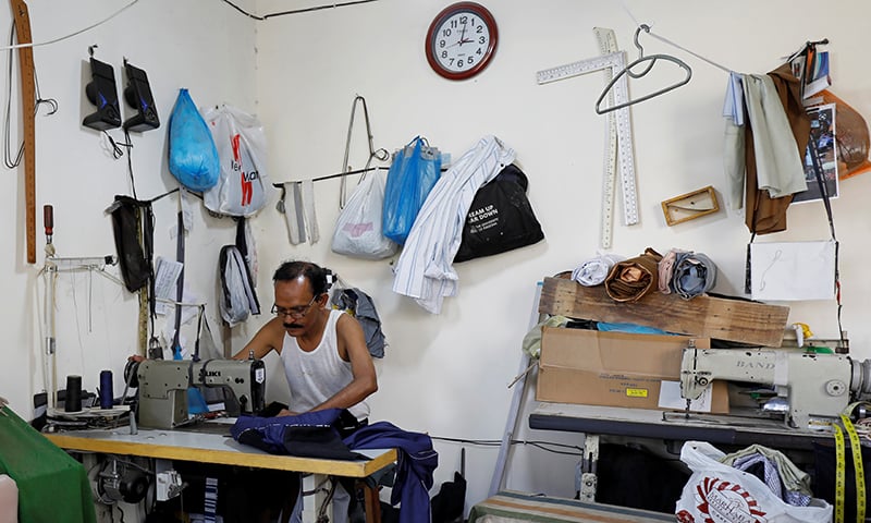 A tailor works in his shop at a market in Karachi, May 12. &mdash; Reuters