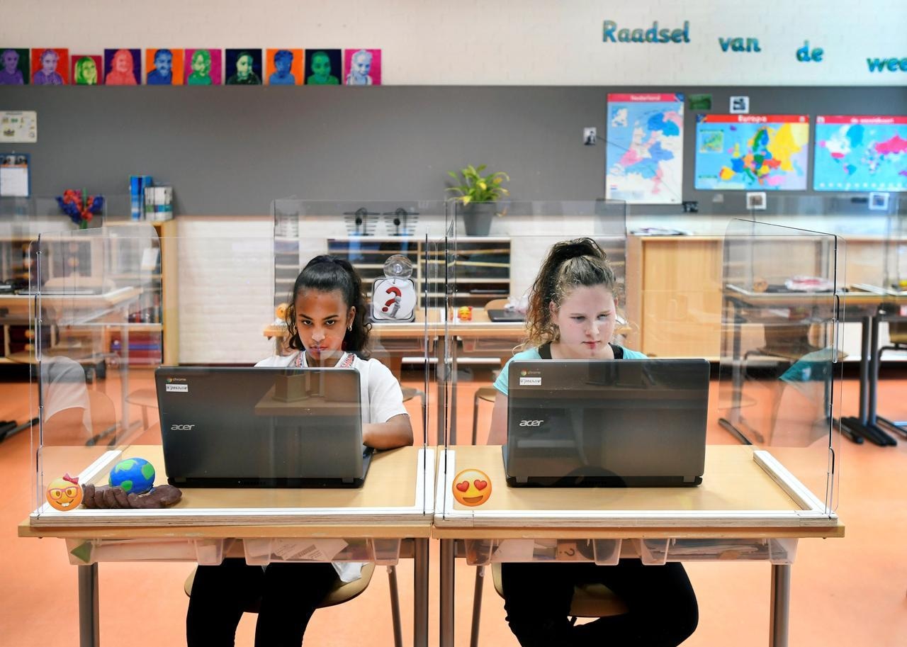 Pupils sit behind partitions made of plexiglass at a primary school in Den Bosch, Netherlands, May 8. &mdash; Reuters