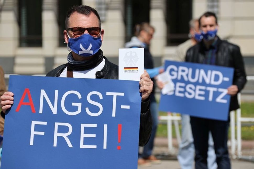 A man wearing a face mask holds a sign and a copy of the German constitution as people participate in a protest by the far-right Alternative for Germany (AfD) party against the government's restrictions in Berlin, Germany, May 16. — Reuters