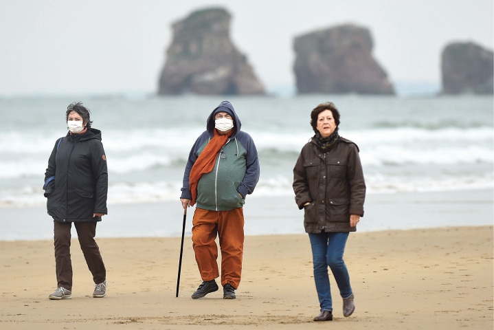 HENDAYE (France): People wearing masks walk along the beach on Saturday.—AFP