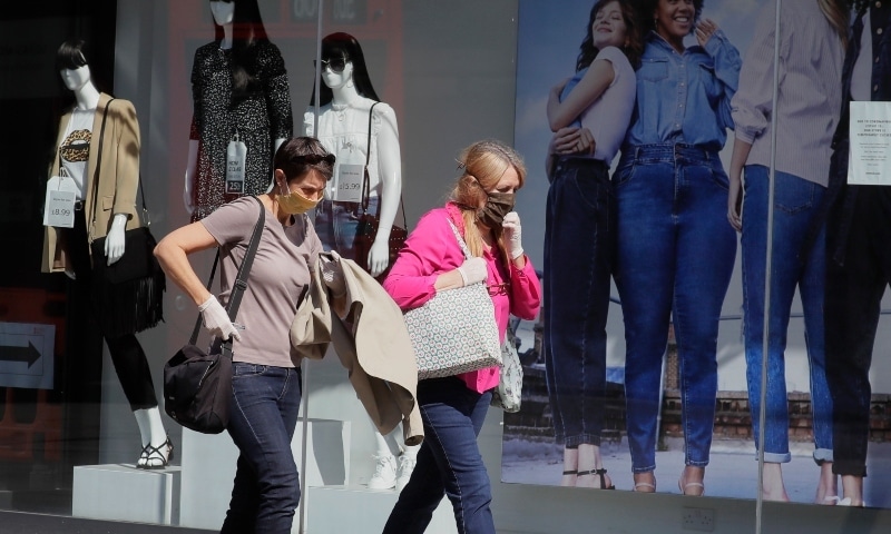 Two women pass a clothing shop in London as the country is in lockdown to help stop the spread of coronavirus on May 19. — AP