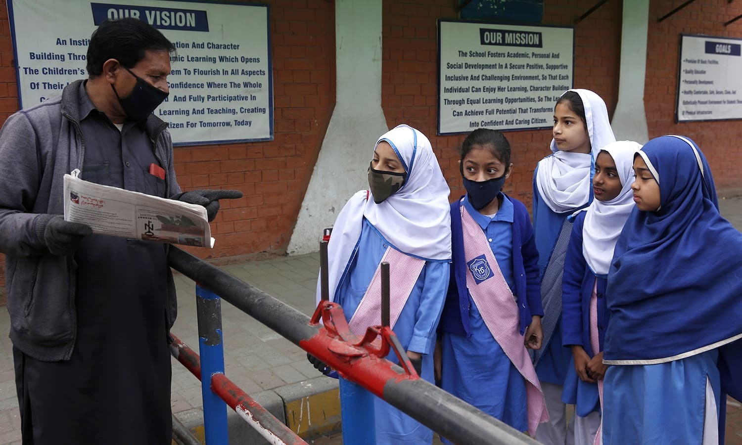 A security guard tells students that their school is closed by authorities to control possible spread of coronavirus, in Lahore, Pakistan, Saturday, March 14, 2020. For most people, the new coronavirus causes only mild or moderate symptoms. For some it can cause more severe illness. (AP Photo/K.M. Chaudary) — Copyright 2020 The Associated Press. All rights reserved.