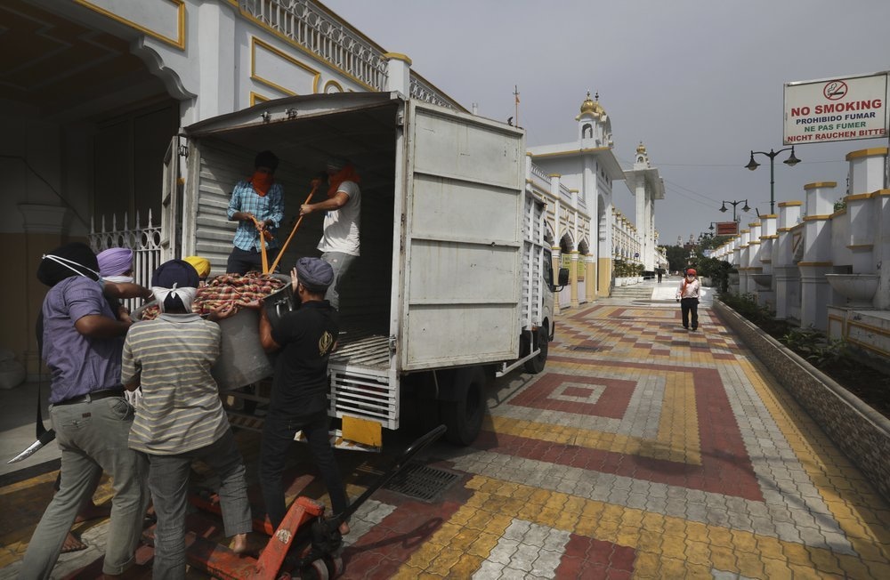 Sikh volunteers help to load food in a van from the kitchen hall of the Bangla Sahib Gurdwara for distribution, in New Delhi, India, May 10. — AP