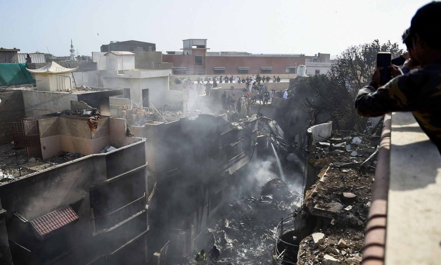 Rescue workers gather at the site after a Pakistan International Airlines aircraft crashed in a residential area in Karachi on May 22. — AFP