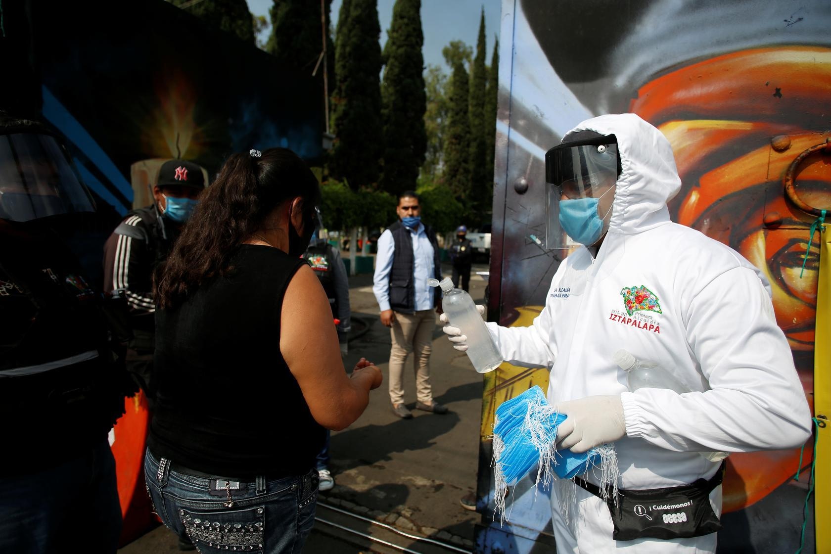 An employee of the municipality of Iztapalapa gives sanitising gel to a woman arriving to the San Nicolas Tolentino cemetery, amid Covid-19 outbreak in Mexico City, Mexico, May 9. &mdash; Reuters