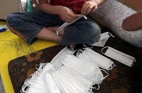 A boy arranges protective face masks at a factory during the outbreak of Covid-19 in Syria, May 11. &mdash; Reuters