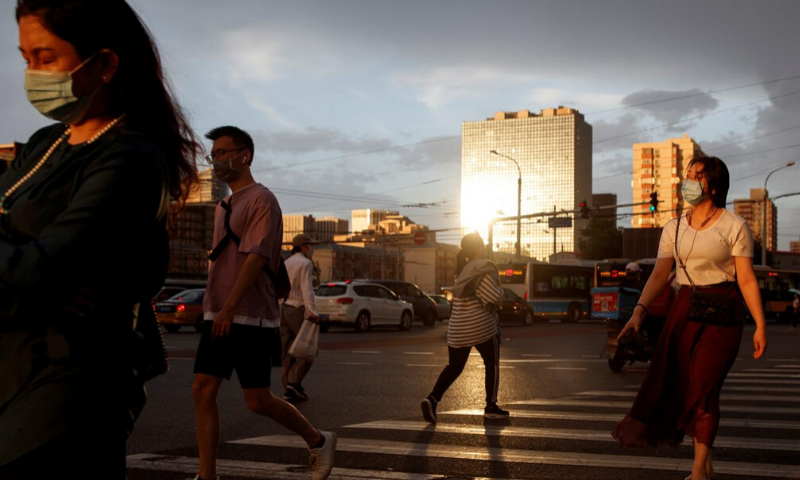 People wear protective masks as they cross a street following an outbreak of the coronavirus in Beijing, China on Thursday. — Reuters