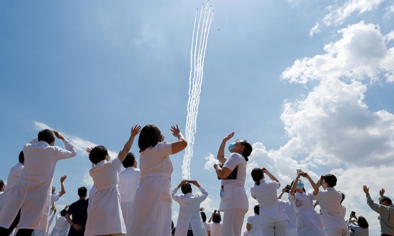 Medical workers react as they watch the 'Blue-Impulse' aerobatic team of Japan Air Self-Defence Force as they fly over the Self-Defence Forces Central Hospital to salute the medical workers at the frontline of the fight against the coronavirus in Tokyo, Japan. — Reuters