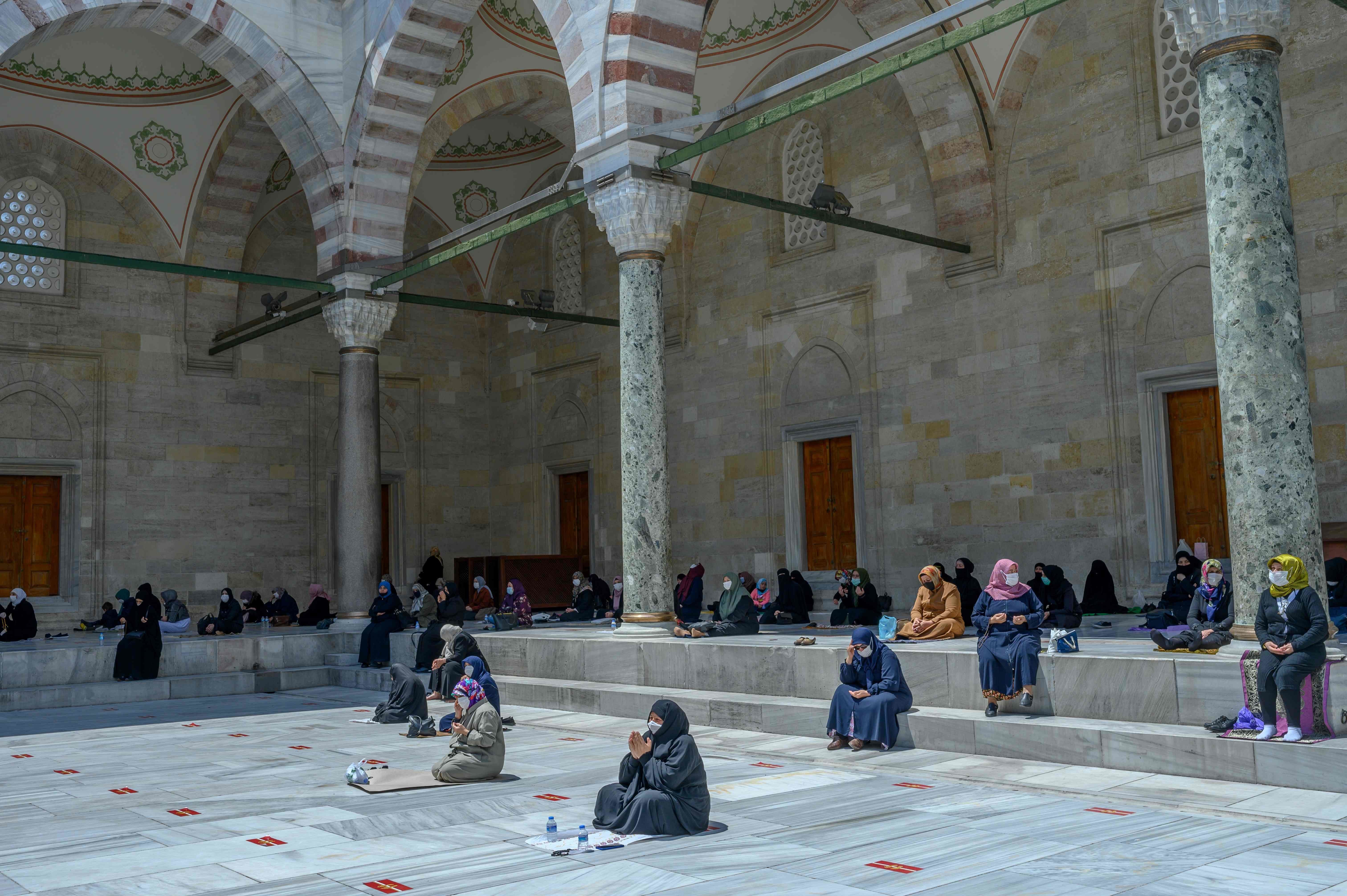 Female worshippers wearing protective facemasks maintain the required social distance during the Friday prayer outside The Fatih Mosque in Istanbul on May 29. &mdash; AFP