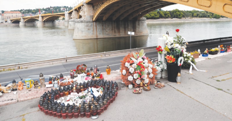 BUDAPEST (Hungary): Flowers and candles are placed near a bridge to honour the victims of the Mermaid boat accident on the first anniversary of the tragedy on Friday.—Reuters