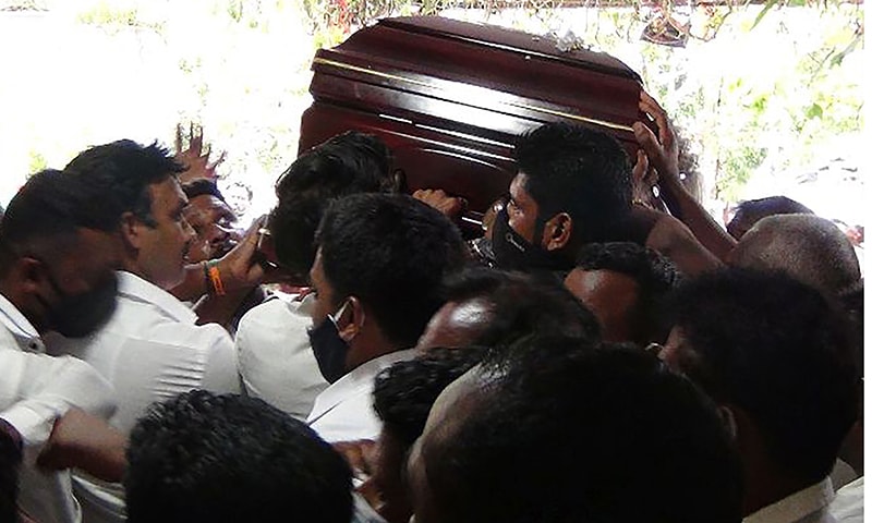 Party supporters breaching social distancing rules carry the coffin of Arumugam Thondaman at his home constituency in Nuwara Eliya district on May 30. — AFP