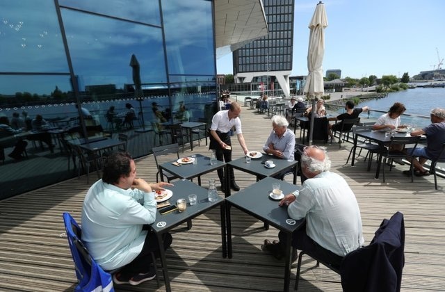 A waiter serves meals to customers who practice social distancing on a terrace of a newly reopened restaurant in Amsterdam, Netherlands, June 1. &mdash; Reuters