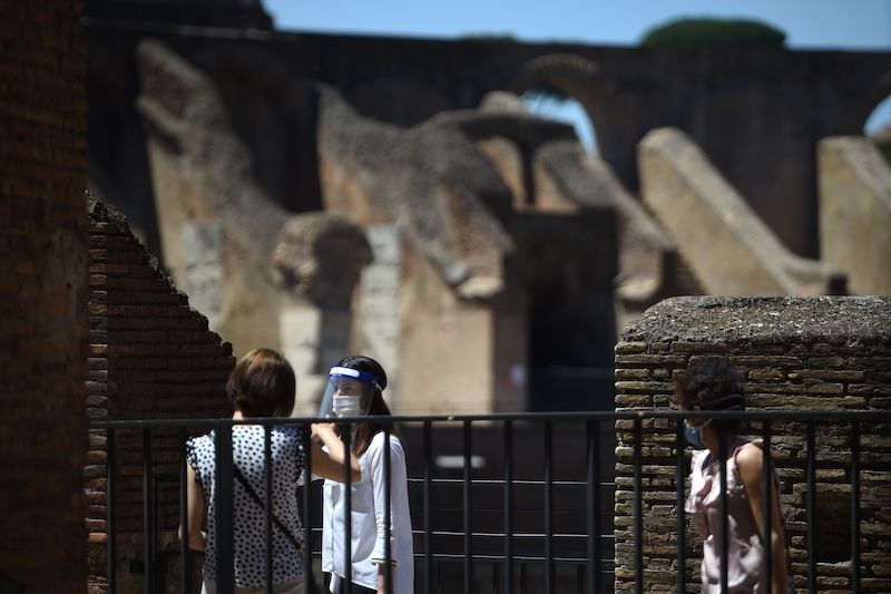 Visitors, one wearing a face mask and shield, walks across the Colosseum monument which reopens to the public on June 1, 2020 in Rome, while the country eases its lockdown aimed at curbing the spread of the COVID-19 infection, caused by the novel coronavirus. - The Colosseum monument reopens on June 1, 2020 after having been closed since March 8, 2020, with adequate sanitary protection for staff and visitors, secure routes, compulsory reservations and modified schedules to avoid crowds at peak times. (Photo by Filippo MONTEFORTE / AFP) &mdash; AFP or licensors