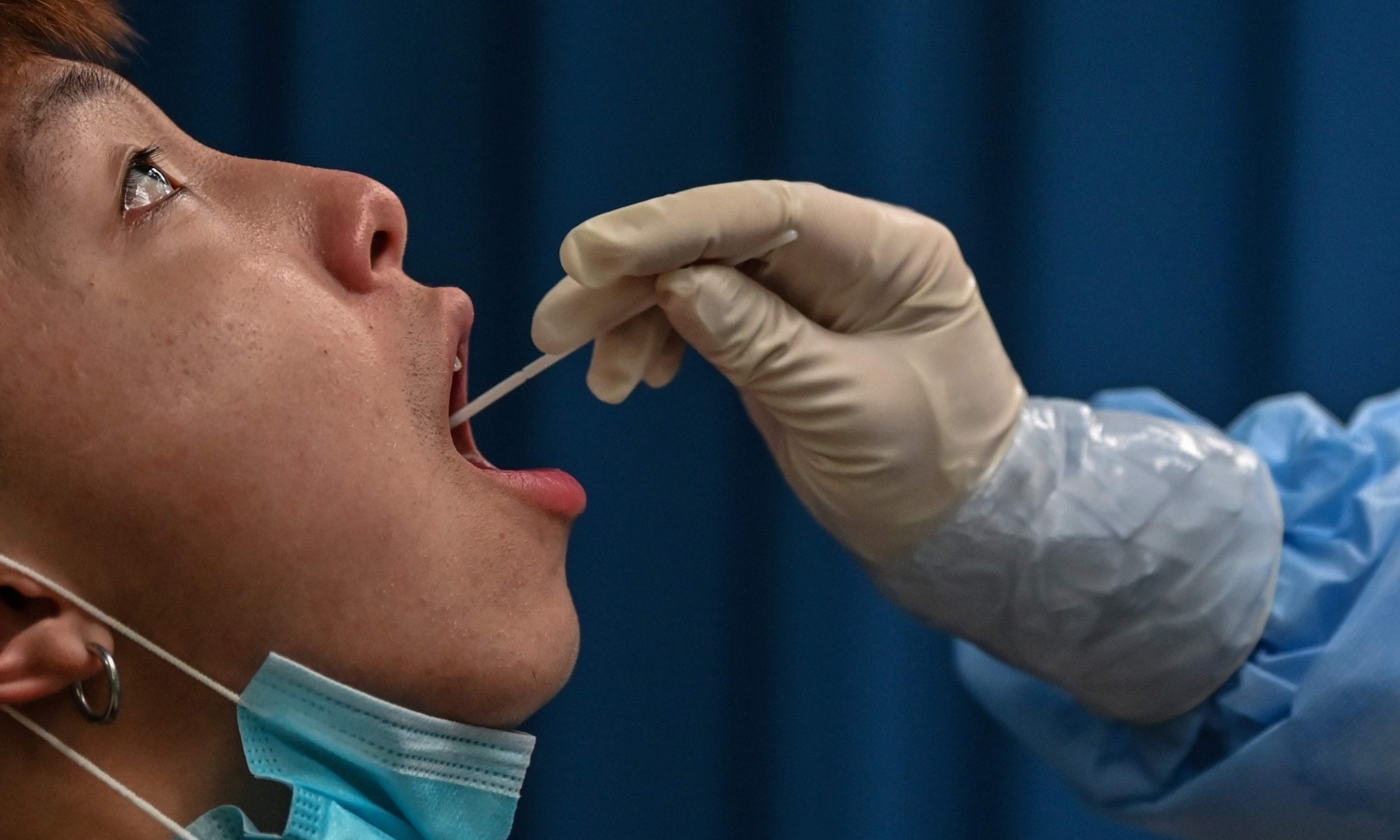 This file photo taken on May 14 shows a medical worker taking a swab sample from a man to be tested for the coronavirus in Wuhan. &mdash; AFP