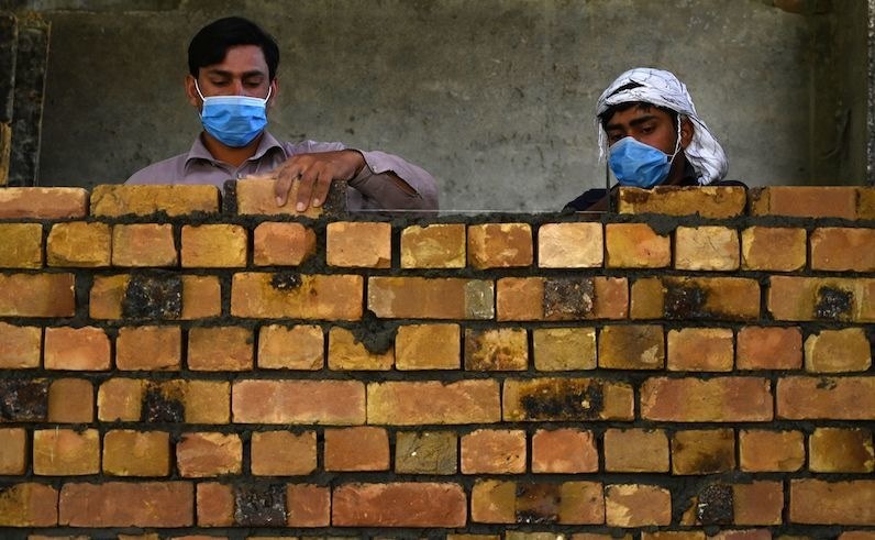 Workers wearing facemasks lay a brick wall at a construction site during a government-imposed nationwide lockdown as a preventive measure against the spread of the COVID-19 coronavirus, in Islamabad on May 6, 2020. (Photo by Aamir QURESHI / AFP) — AFP or licensors