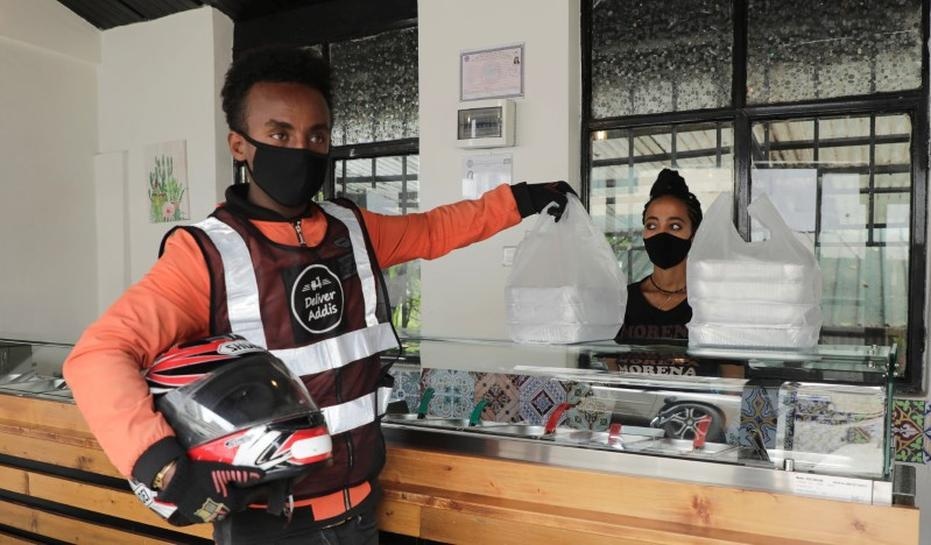 Biniam Nigussie, 21, a Deliver Addis motorbike rider picks up lunch boxes from La Morena restaurant to be delivered to clients working from home due to the spread of Covid-19 in central Addis Ababa. — Reuters