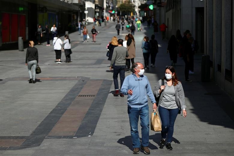 A couple wear protective masks as they walk in central Madrid, Spain, March 13. &mdash; Reuters