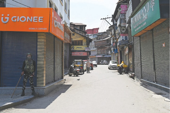 SRINAGAR: An Indian paramilitary soldier stands guard near closed shops after four fighters were killed by government forces in India-held Kashmir on Monday.—AFP