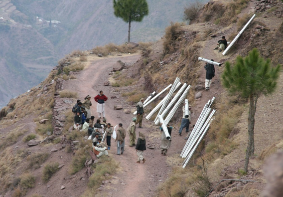 People carrying tin sheets to construct roofs in Neelum Valley in December 2005. Many villages were accessible by jeeps prior to the earthquake, but landslides and other hazards disrupted this transport for up to one year. This particular village was a two hour walk from the road when walking without a load. — Photo by Das