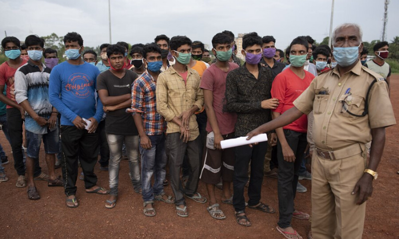 A security officer controls the queue of migrant workers from West Bengal state waiting to board a bus to catch home bound trains in Kochi, in the southern Indian state of Kerala on Wednesday. &mdash; AP