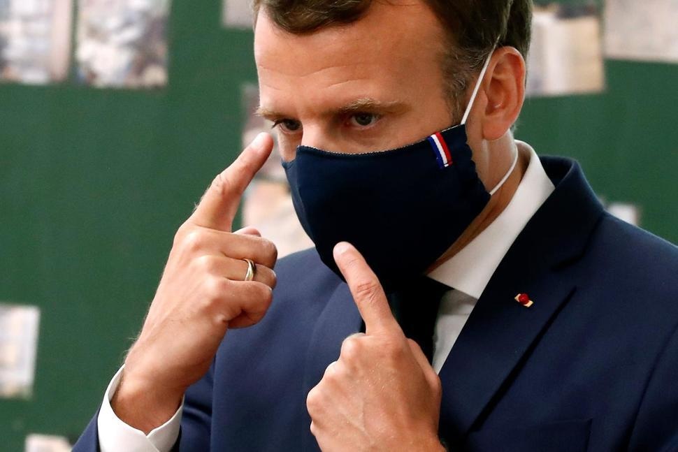 In this May 5 photo, French President Emmanuel Macron wears a protective face mask as he speaks with schoolchildren at the Pierre Ronsard elementary school, outside Paris. &mdash; AP