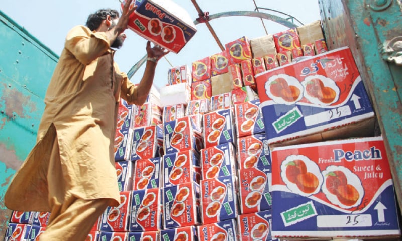 A worker loads peach boxes on a truck in Swat for transportation to other districts. &mdash; Dawn