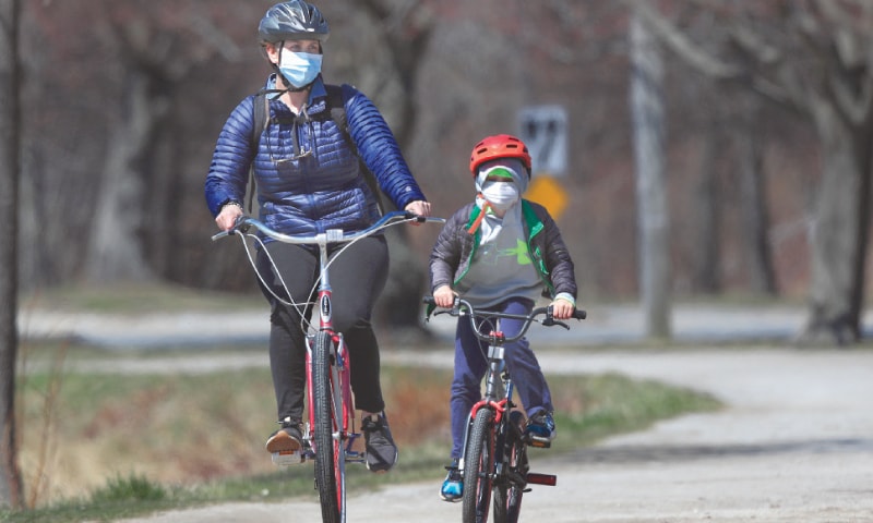 Portland (Maine, US): Bicyclists wear pandemic masks while riding in Portland.—AP Portland (Maine, US): Bicyclists wear pandemic masks while riding in Portland.—AP