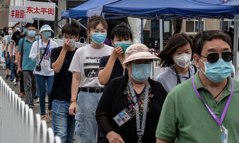 People wearing face masks gather at an outdoor area during a mass testing for Covid-19 at the Jinrong Street testing site in Beijing on June 24. &mdash; AFP