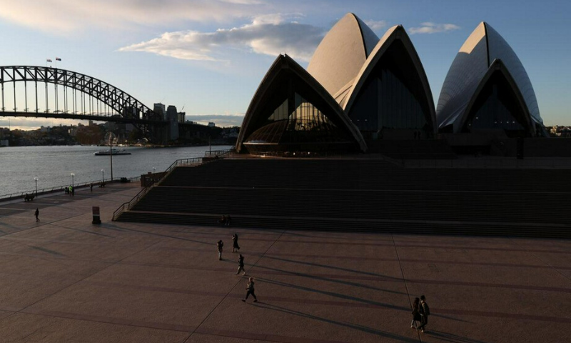 People are seen walking in front of the Sydney Opera House and Sydney Harbour Bridge following the easing of restrictions implemented to curb the spread of the coronavirus on Tuesday. &mdash; Reuters