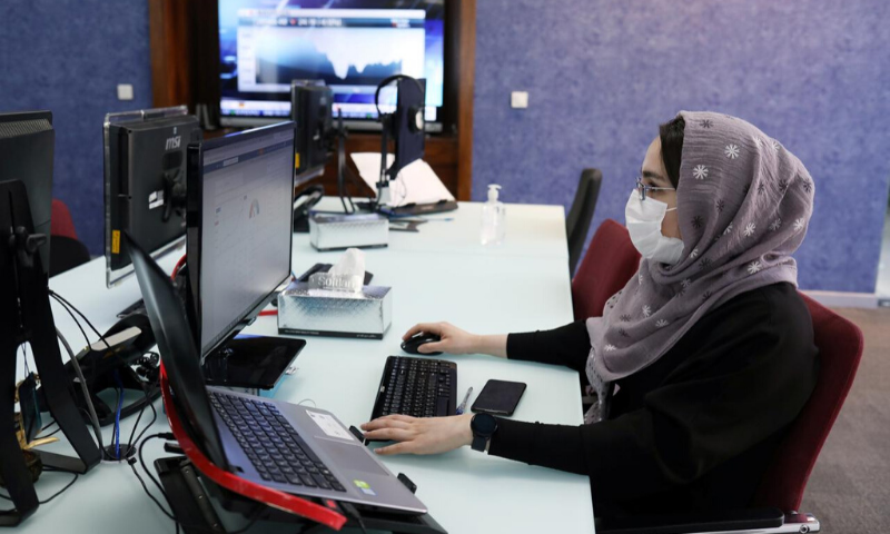 An employee of a stock brokerage firm wearing a protective face mask monitors stock prices on her computer, following the outbreak of the coronavirus in Tehran, Iran. &mdash; Reuters/File