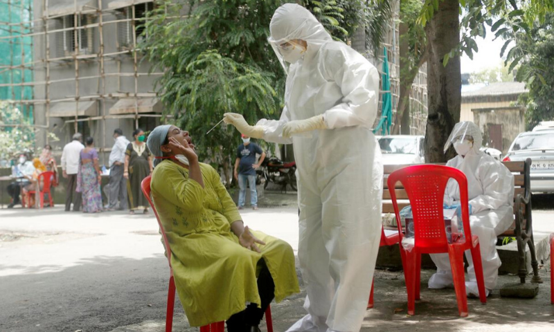 A health-worker wearing personal protective equipment collects a sample using a swab from a woman during a check-up campaign for the coronavirus in Mumbai, India. &mdash; Reuters