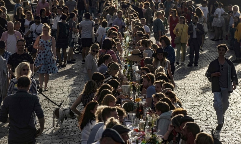 People sit at a half kilometre-long table set up on the Charles Bridge in Prague to celebrate the end of the restrictions linked to the new coronavirus pandemic on June 30. &mdash; AFP