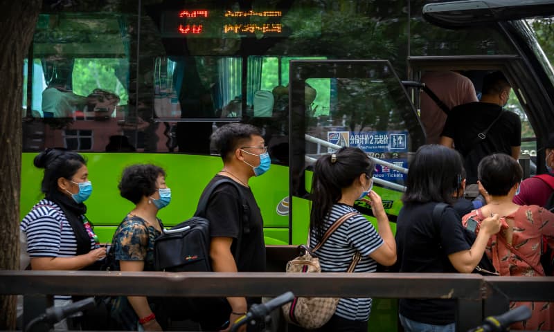 People wearing face masks to protect against the new coronavirus line up for a bus in Beijing on Friday, July 3, 2020. — AP