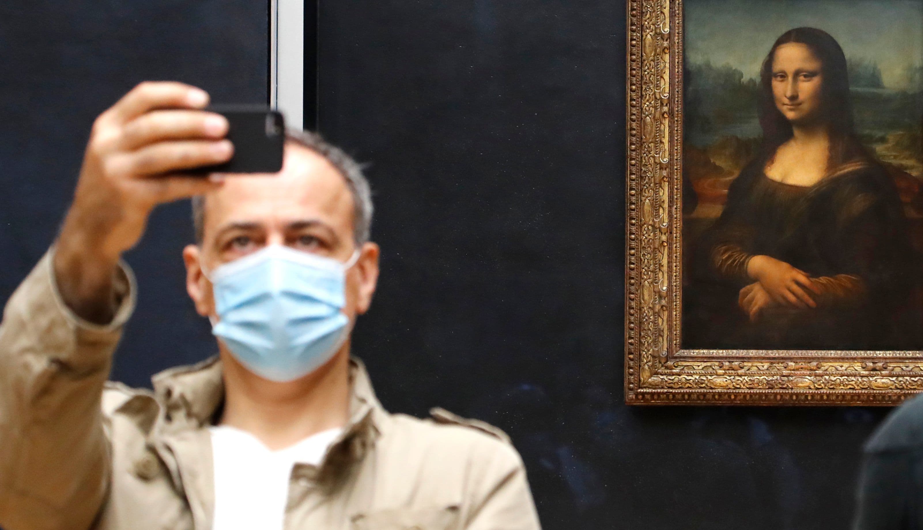 A visitor wearing face mask takes a picture in front of Leonardo da Vinci's masterpiece "Mona Lisa" also known as "La Gioconda" at the Louvre Museum in Paris on July 6. &mdash; AFP