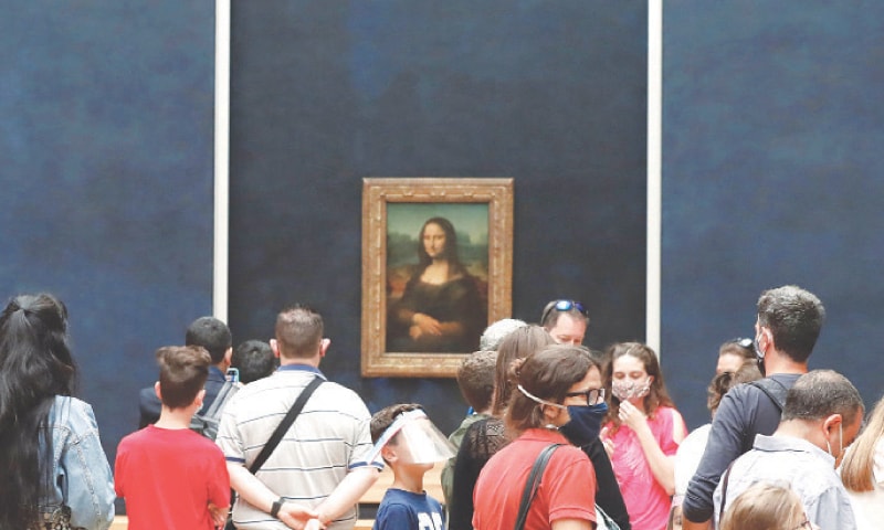 PARIS: Visitors wearing masks gather in front of Leonardo da Vinci’s masterpiece ‘Mona Lisa’ at the Louvre Museum on Monday. The museum reopened its doors after months of closure due to lockdown measures linked to the novel coronavirus. The crisis has already caused more than 40 million euros in losses at the Louvre.—AFP