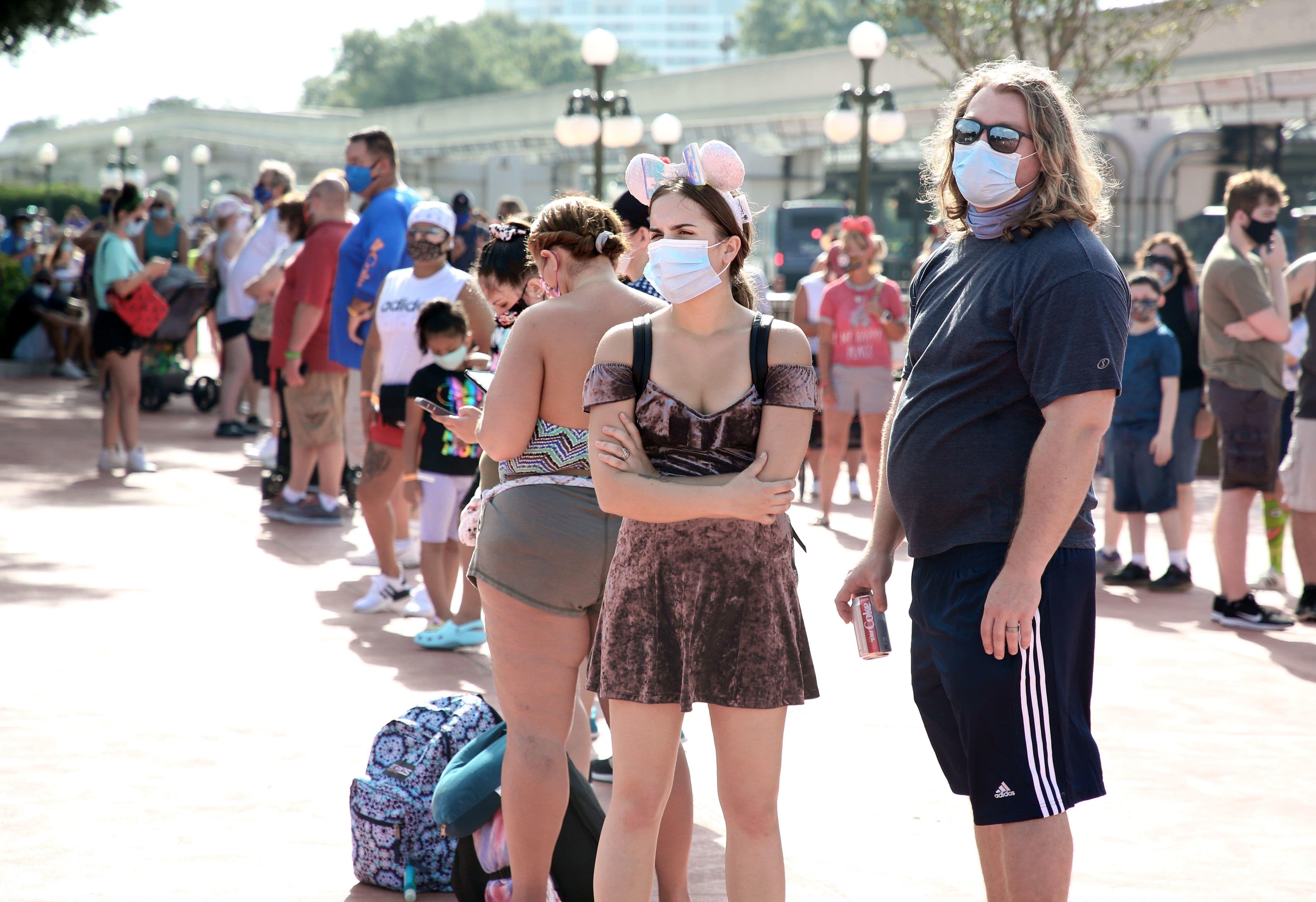 Guests wearing protective masks wait outside the Magic Kingdom theme park at Walt Disney World in Orlando, Florida, on July 11. &mdash; AFP