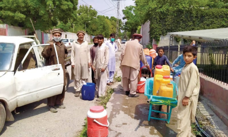 People get drinking water from a roadside tap in Parachinar. &mdash; Dawn
